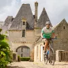 Man smiling while riding a bike with a stone castle in the background