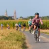 Group of teenagers on bikes, riding through a road surrounded by tall weeds