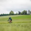Man riding a bike on a road next to an empty valley of grass