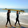 Two girls carrying a yellow surfboard over their head