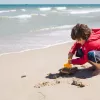 Boy on the beach, playing with the sand and a scooper