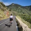 Person riding their bike on a road with large, grassy mountains in the distance