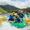 Two groups of families on green rafts, paddling in a river