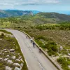 Group of people biking on an empty road, surrounded by a grassy valley