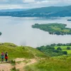 Two people descending a grassy hill towards a large lake