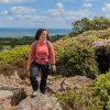 Woman wearing a pink shirt and a backpack, hiking on a rocky hill