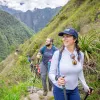 Woman and man walking on a dirt trail, smiling and looking out towards large hills