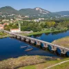 Long stone bridge with a river underneath, leading to a small town