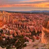 Sky view of a valley of orange canyons with the sunset in the distance