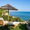 Two sun chairs below an umbrella on the coast of Portugal.