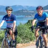 Man and woman biking on a road, with the ocean in the background