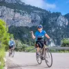 Group of people biking on a road with large mountains and cliffs in the background