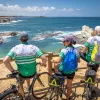 Group of bikers leaning on railings, looking out towards the ocean