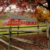 Red barn with a large field and wooden fence in front