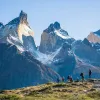 Large mountains with a group of people walking on a smaller mountain
