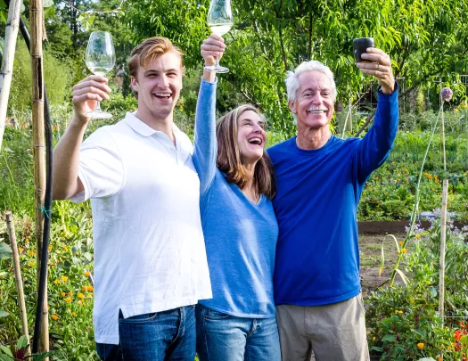 Three guests cheersing various beverages, trees behind them.