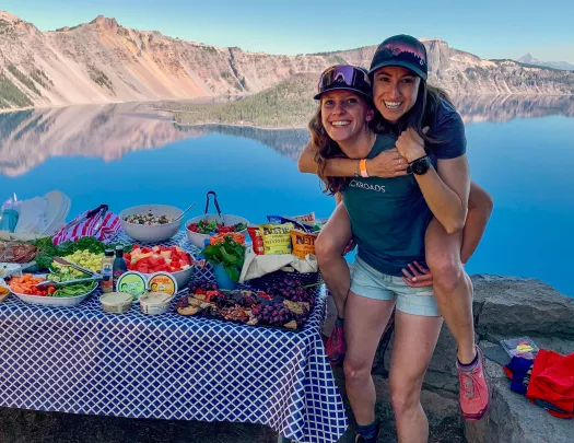Two guests/leaders next to lunch spread, one is on the other's back.