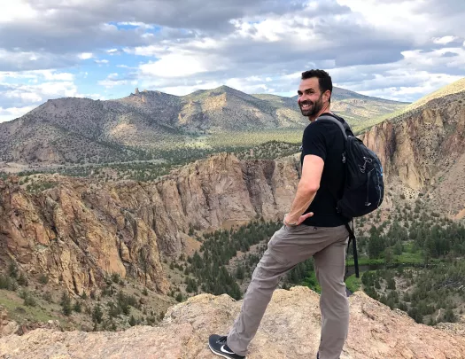 Guest standing on cliff's edge overlooking Smith Rock Park.