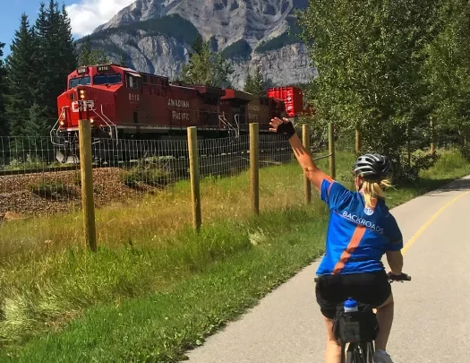 Guest cycling past train, waving to it.