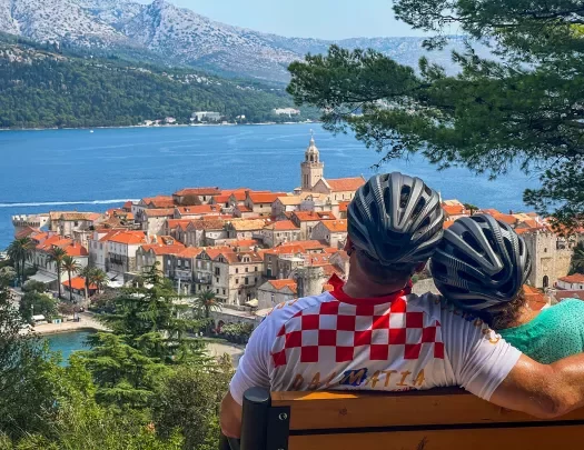 Two guests in bike gear on bench, overlooking Dalmatian Coast.