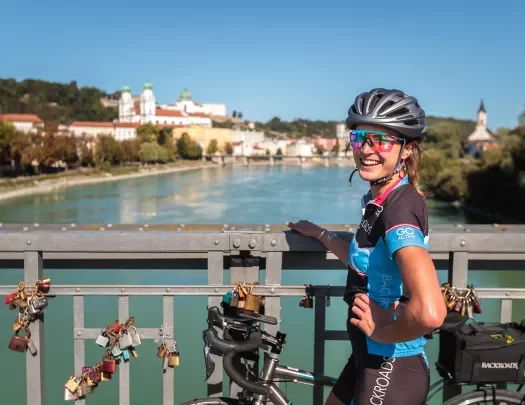Biker posing on the bridge railing across the Danube River.