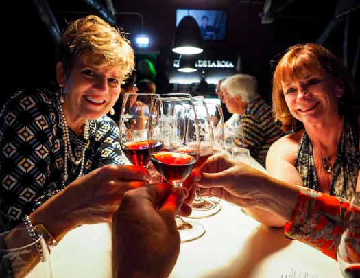 People saying cheers with glasses of red wine.