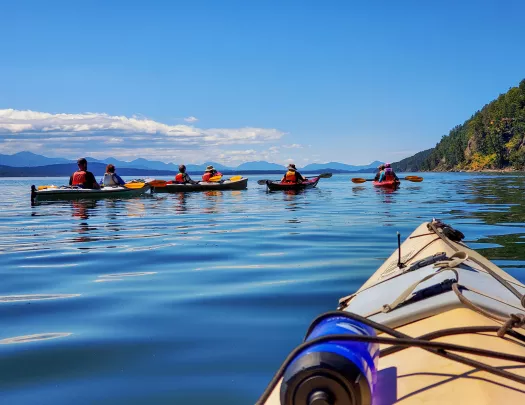 Point of view shot of  guests kayaking, mountains in background.