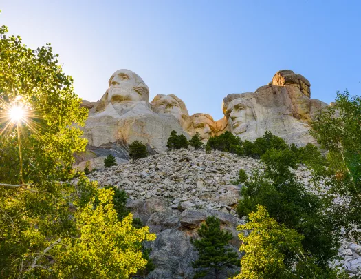 Sun shining on Mount Rushmore and trees