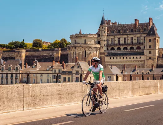 Guest cycling in French town, Château Royal d'Amboise in background.