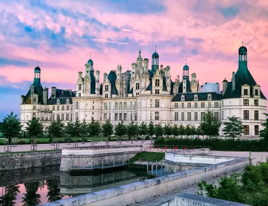 Wide shot of the Château de Chambord, purple sunset behind.