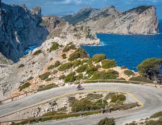 Biker riding around a bend on the coast of Mallorca.