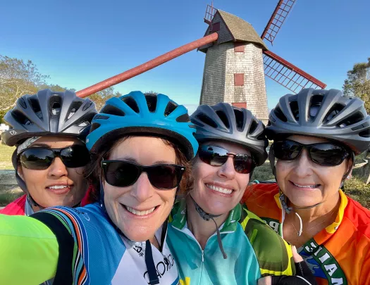 Group of four guests in glasses, windmill behind them.