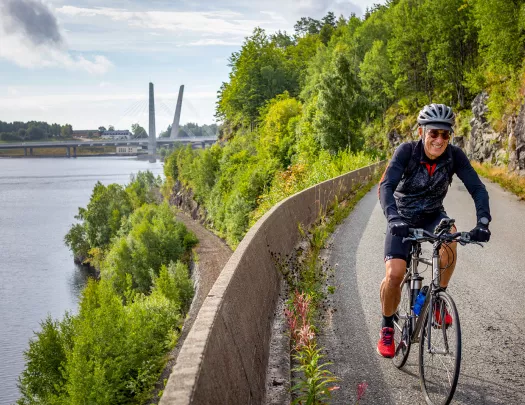 Biker riding along a river in Norway