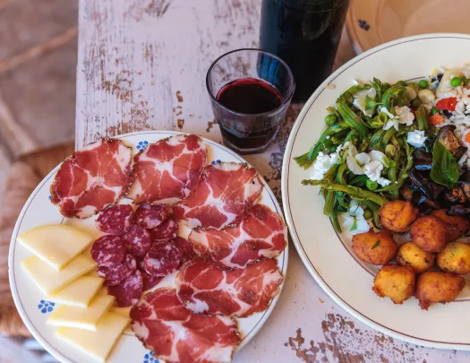Two food platters, cheese, cured meats, rice and salads.