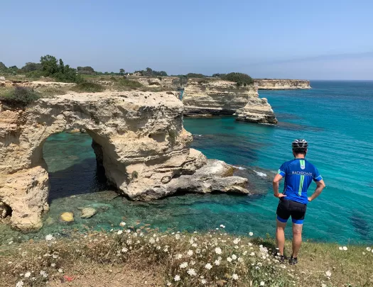 Guest overlooking white-rock coast, light blue water in background.