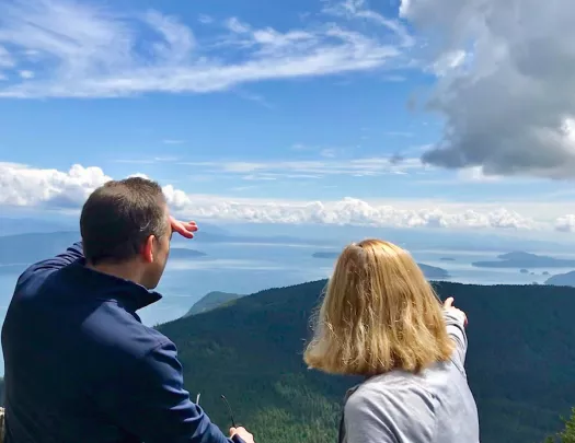 Two guests looking out over cloudy vista, forest below them.