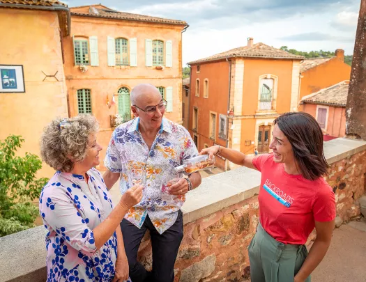 Two guests and a leader, leader pouring wine for guests, on house balcony.