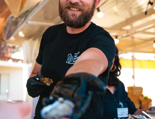 POV shot of local handing guest an oyster.