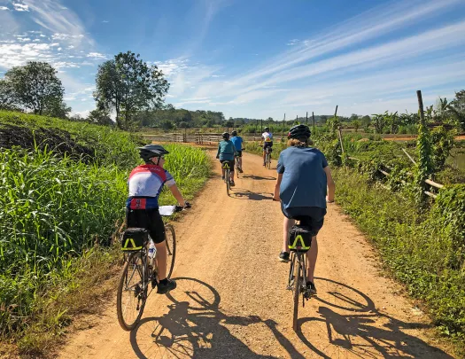 Backroads guests riding along a dirt path in Thailand