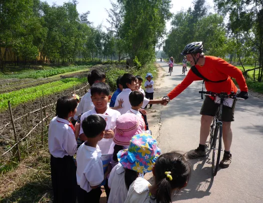 Backroads biker stopping to talk to children in Vietnam