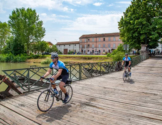 Cyclists crossing a wooden bridge in Veneto