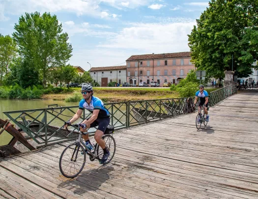 Cyclists crossing a wooden bridge in Veneto