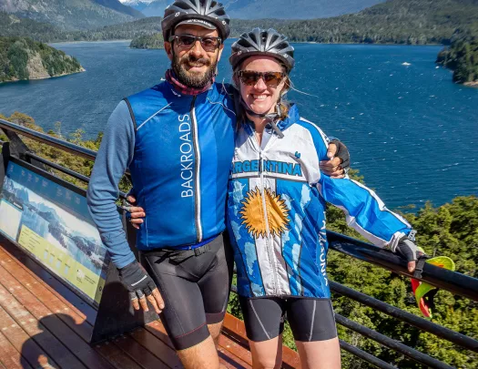 Two guests on bridge, overlooking lake, mountains.