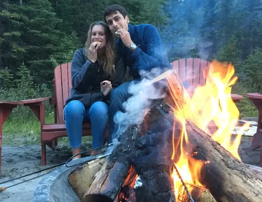 Two guests eating smores around a fire.