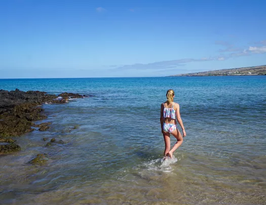 Woman walking in the ocean by the beach in Hawaii