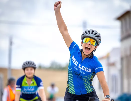 Woman raising her arm in triumph while biking