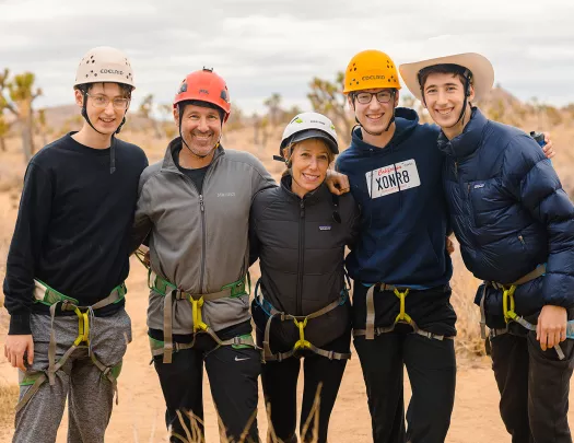 Group of five smiling for camera, all in climbing harnesses.