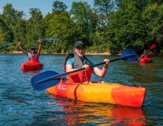 three guests kayaking, one is celebrating in background.