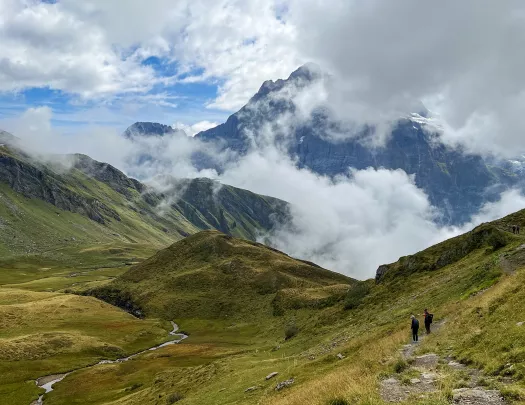 Wide shot of mountainous vista, two guests in distance.