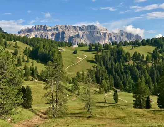 Wide shot of mountainous vista, small hilltop house in middleground.